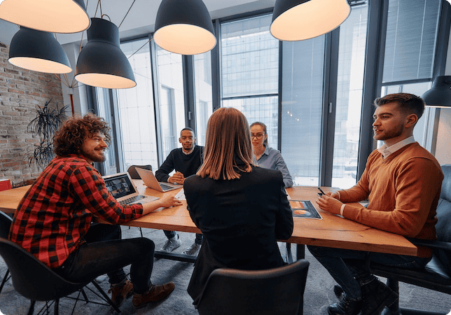 Several people in a meeting room, looking at an analytics dashboard and discussing results.